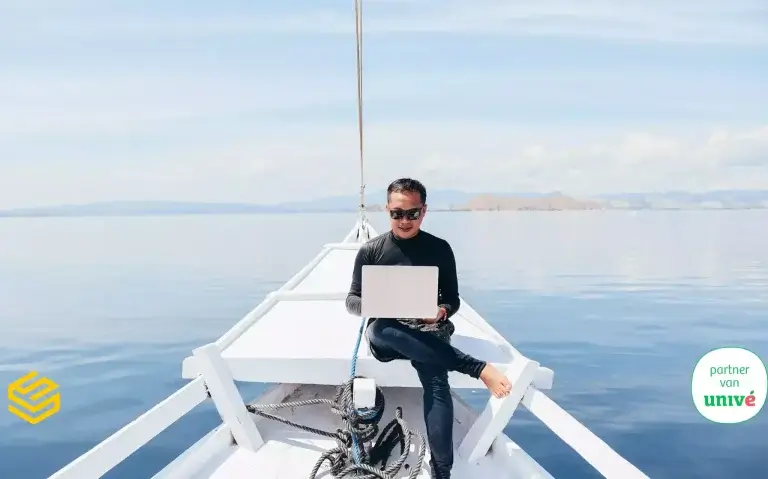 Man op een boot met laptop aan het werk