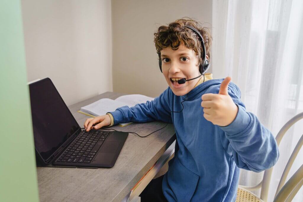 Jongen aan het werk op zijn computer met zijn headset op.